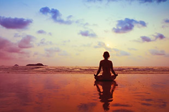 Holistic Psychology practice - women meditating in sunset