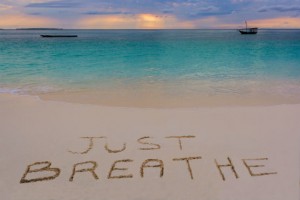 Calm beach with writing on sand Just Breathe