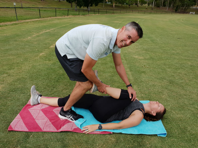 Personal Trainer stretching client on fit ball